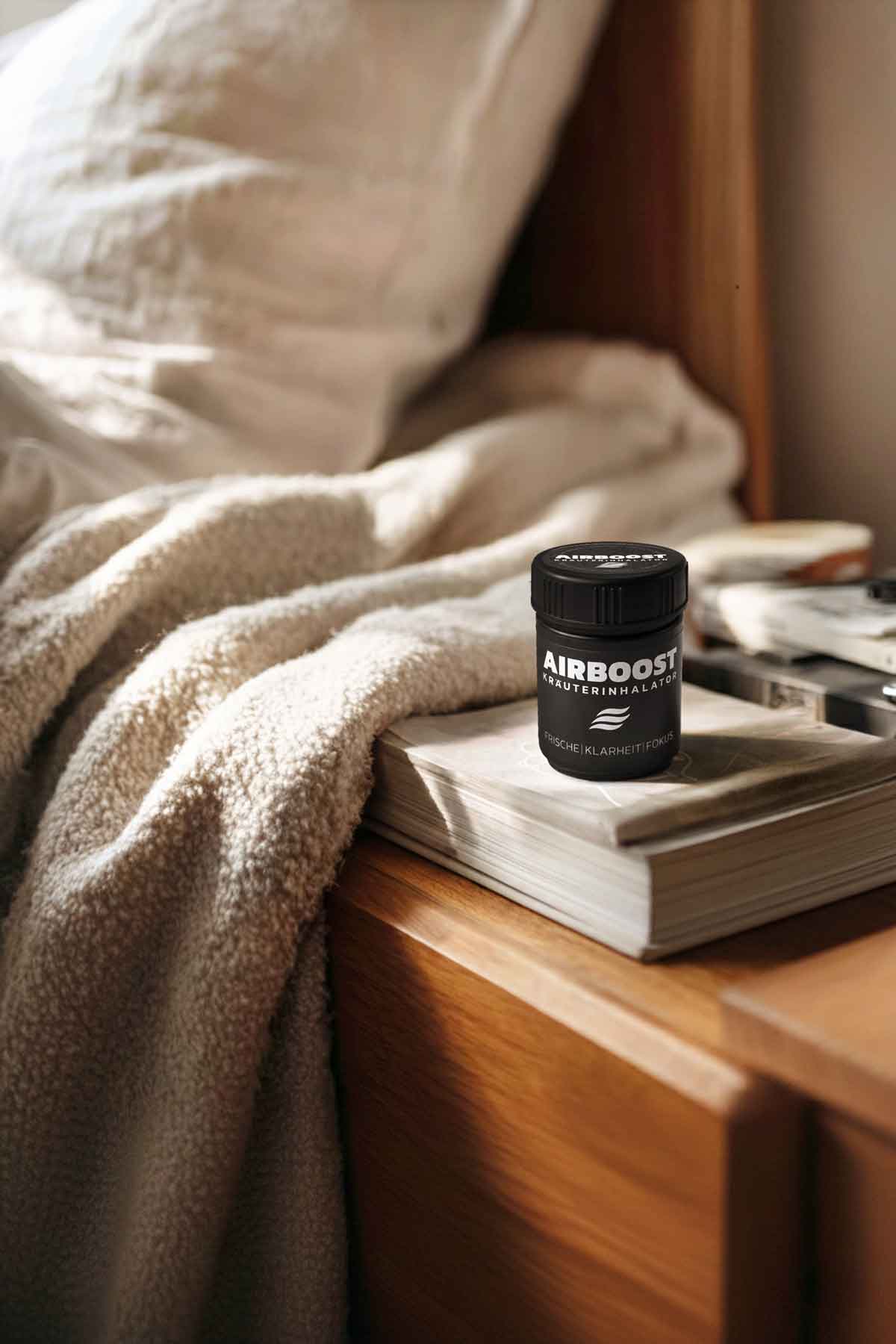 AIRBOOST Kräuterinhalator für mehr Frische, Fokus im Alltag auf einem Buch neben dem Bett im Schlafzimmer
