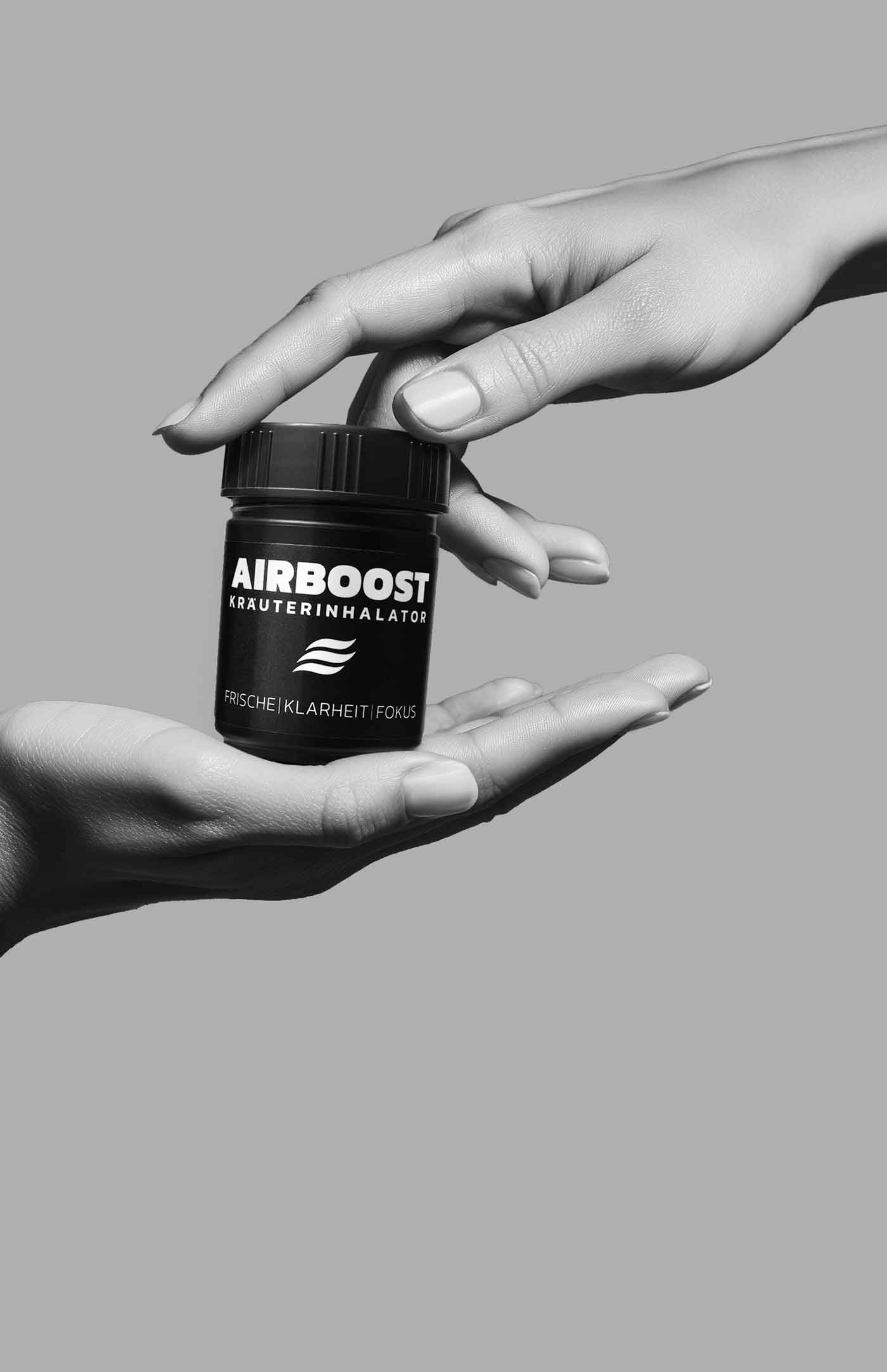 AIRBOOST Kräuterinhalator für mehr Fokus im Alltag - Hand greift auf den Drehverschluss während die andere die Dose hält 