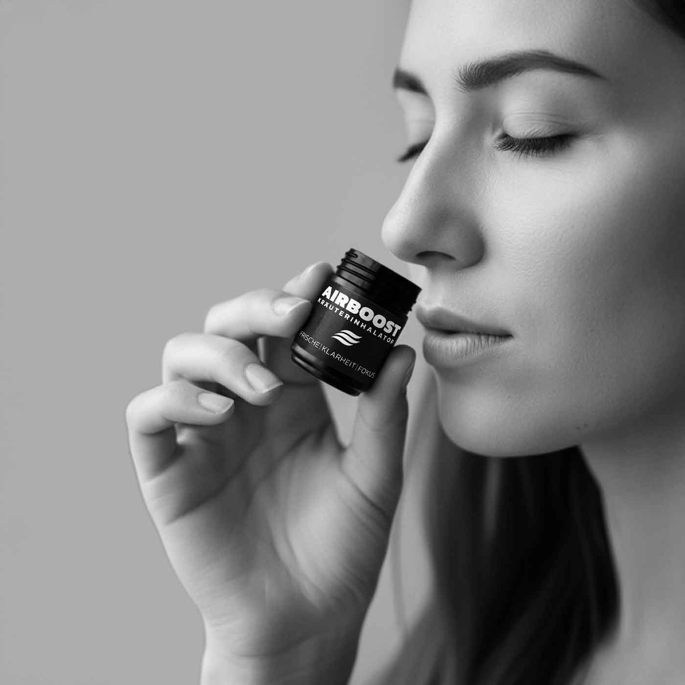 AIRBOOST Kräuterinhalator Anwendungsbild - Frau riecht an einer offenen Dose - ihre Augen sind geschlossen