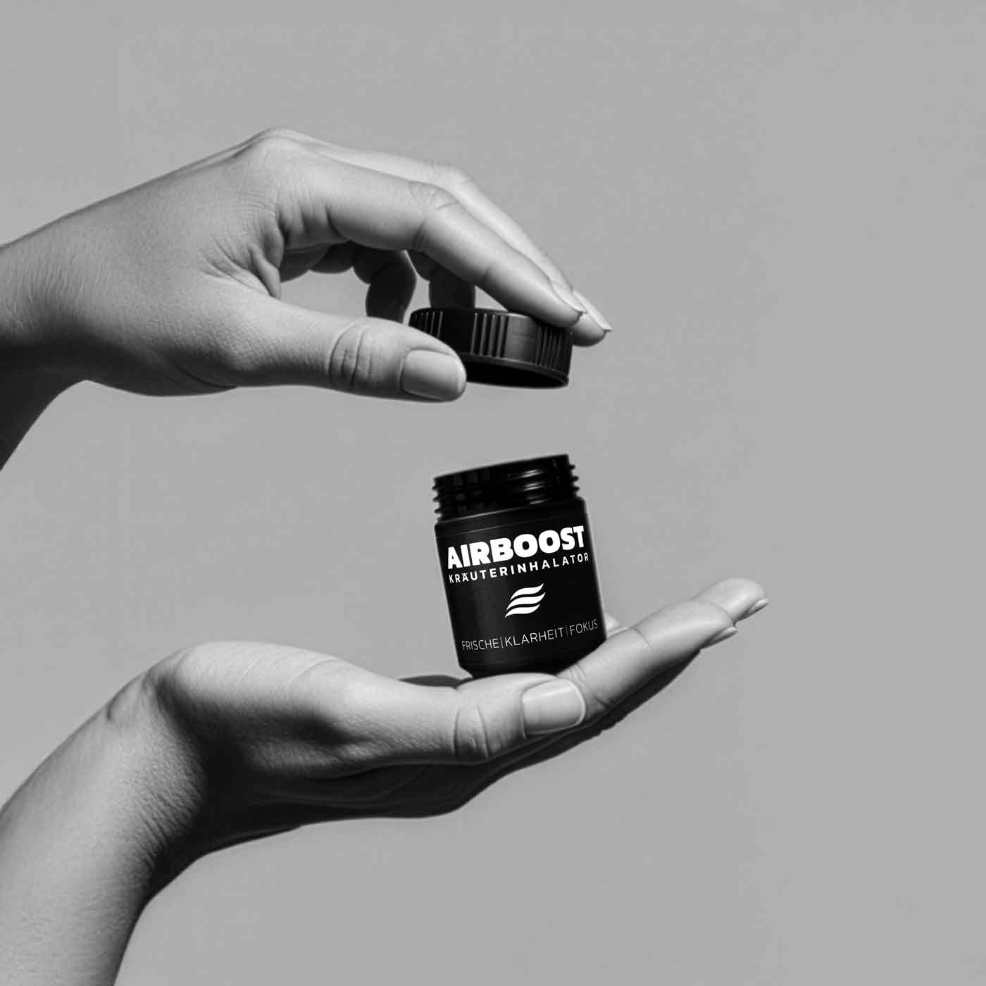 AIRBOOST Kräuterinhalator Anwendungsbild - Hand öffnet die Dose mit Drehverschluss während die andere Hand die Dose hält