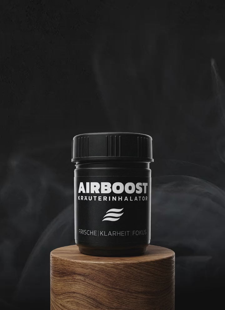AIRBOOST Kräuterinhalator für mehr Frische, Klarheit und Fokus auf einem Holztisch im Hintergrund mit leichtem Rauch als Aromavisualisierung.